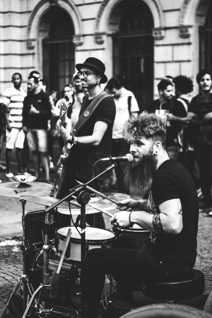 Energetic street musicians performing with guitar and drums, captivating a diverse crowd.